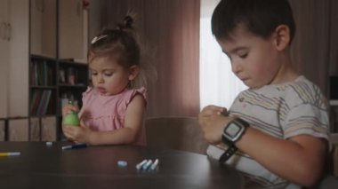 Erkek ve kız kardeş, Easte için hazırlanıyor dekoratif yumurtaların üzerine çizim yapıyorlar. Çocuklar için ev kursu. Çocuklar için eğitim egzersizleri.