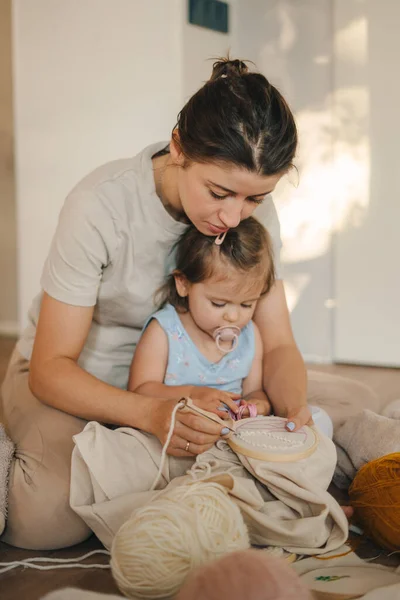 Caucasian mother and daughter knitting and embroidery during leisure time at home. Needlework concept. Happy and relaxed enjoy free time