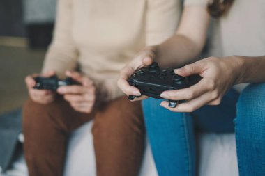İki kadının el ele tutuştuğu oyun kumandası, video oyunları oynadığı yakın plan görüntüler. Video oyunu. Mutlu bir aile. Bilgisayar eğlencesi.