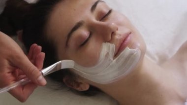 Güzellik uzmanları, kadın yüzüne nemlendirici cilt için vitamin kremi sürüyor güzellik salonlarında yaşlanma karşıtı kozmetik prosedürler uyguluyor. Kozmetik prosedürü. Yüz Yüzü