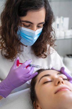 Güzellik uzmanının elini kapat. Güzellik kliniğinde kadın yüzüne doldurucu enjekte et. Kadın kozmetik müşterisi kozmetik güzellik salonunda yüz bakımı yapıyor..