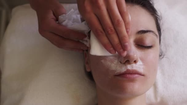 在美容师的手术过程中 一个女人的头像 清洁她的脸 面罩后用特殊擦拭的美容师擦脸 — 图库视频影像