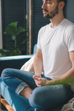 Genç bir adamın yoga yaptığı ve kanepede meditasyon yaptığı fotoğraf. Konsept tasarım için. Ev konforu.