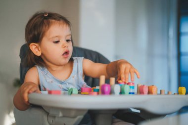 Güzel bebek evde ahşap çerçeve yapboz geometrik figürlü oyuncaklarla oynuyor. Bebekler renkli bir oyuncakla oynarlar. Çocuk gelişimi.