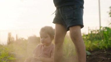Erkek ve kız yerde oturuyor, çocuk ayağa kalkıyor ve kirli giysilerini silkeliyor, bacaklarını sallıyor ve toz yapıyor. Yaz tatili eğlencesi. Mutlu aile