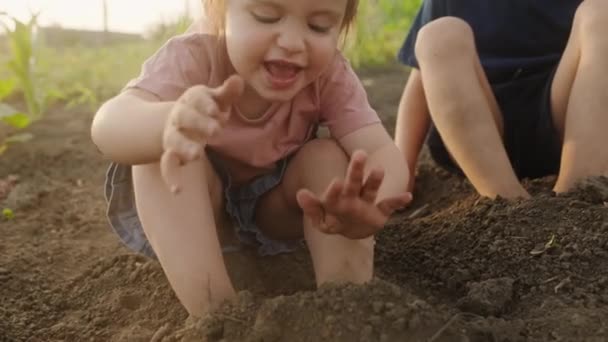 Holčička Sedí Vedle Svého Bratra Zemi Zahradě Dívka Strká Nohy — Stock video