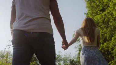 El ele tutuşan iki genç aşığın arka görüntüsü. Birbirlerine aşık sevgililer. Doğada yürüyorlar. Güzel bir çift eğleniyor. Birlikte geçirdiğimiz zaman.