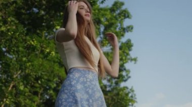 Yeşil yaz parkında poz veren kızıl saçlı güzel bir genç kadın. Başarı, özgürlük ve mutluluk kavramı
