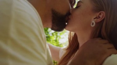Erkek, yaz doğasında öpüşürken kız arkadaşını nazikçe okşar. Park, aşk ve çift doğada romantizm, yaz ve sevgililer günü için öpüşürler.