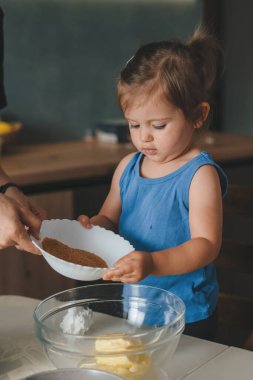 Kafkas bebek onları karıştırmak için şeffaf kaseye malzeme ekliyor. Pişirmek güzel ve komik. Eller iş başında