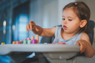 Küçük bebek tahta bir manyetik yapıcının içinde masada oynuyor, evde yapboz yapmayı öğreniyor. Erken gelişim. Bu sırada çocuklarla oynamak