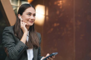 Cafe 'de oturmuş müzik dinlerken gülümseyen ve kameraya bakan, şık giyinen genç bir kadının alçak açısı.