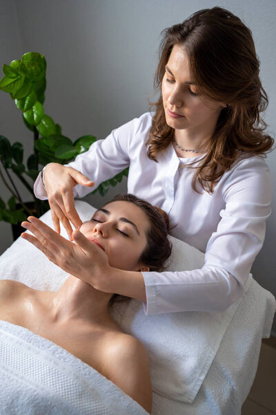 Beautician woman making lymphatic drainage face massage or facelifting massage at the beauty salon. Face Treatment. Beauty injection procedure for skincare.