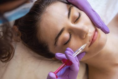 Kozmetologların elleri dudak büyütme için iğne yapıyor. Güzellik salonunda kadın kozmetolojisi..