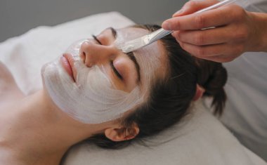Beyaz kadın güzellik tedavileri yapıyor, spa tedavisi uyguluyor ve yüzüne krem sürüyor. Yüz bakımı. Kozmetik prosedürü. Sağlıklı yaşam tarzı, sağlık..