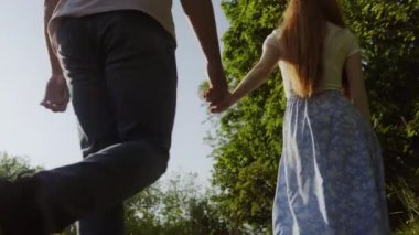 Bir çiftin el ele tutuşup ülke sahasında birlikte yürüdüğünü gördüm. Bahar batımı. Arkadan bak. Mutlu aile, yaz, tatil. Aile Günü.