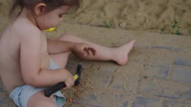 Bahçede çekiç oyuncağıyla oynayan çekici küçük bir kızın görüntüsü. Dışarıda oynayan pozitif çocuk. İnsan portresi.