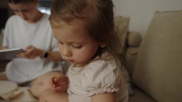 Menina Sentada Sofá Brincando Com Fios Multicoloridos Enquanto Sua Mãe — Vídeo de Stock