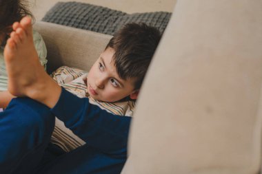 Evdeki kanepede iki küçük çocuğun, erkek ve kız kardeşlerin kapalı bir portresi. İnsanların yaşam tarzı portresi. Duygusal ifade. Ev istirahatı.