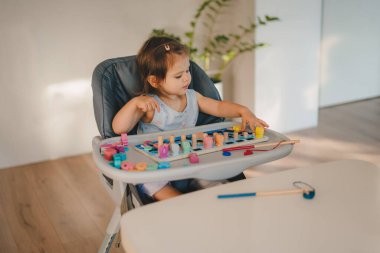 Küçük beyaz kız, ev içinde tahta ayıklayıcı oyuncaklarla oynuyor. Yaratıcı sanat projeleri. Bilişsel beceri gelişimi. Etkin oyun zamanı eğlencesi.