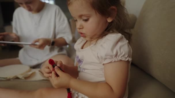 ウール糸のボールで遊んでいるソファーに座っている白人赤ん坊の少女 — ストック動画