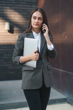 Güzel bir kadın işe gidiyor, yürüyor ve ofisinin yakınında telefonla konuşuyor. İnsanların yaşam tarzı portresi. Güzel genç bayan..