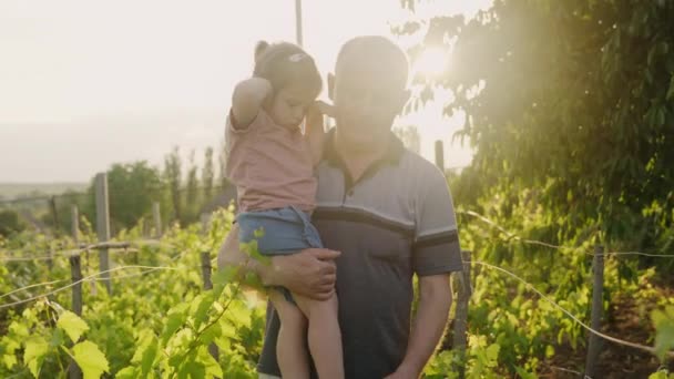 小さな赤ん坊の少女は ブドウ栽培を調べながら庭で祖父と時間を過ごしました 手が握っている リトルガーデン — ストック動画