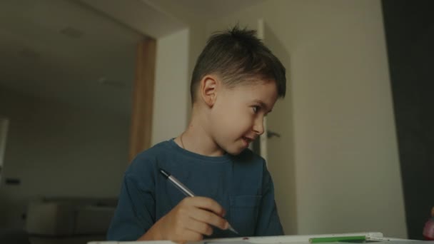 Menino Escola Sorrindo Fazendo Lição Casa Enquanto Estava Sentado Mesa — Vídeo de Stock
