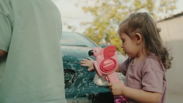 Kız Oğlan Evin Bahçesinde Sabun Balonu Tabancasıyla Arabayı Yıkıyorlar Çocuklar — Stok video