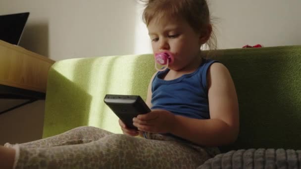 Criança Pequena Concentrada Jogar Console Videogame Portátil Sentada Sofá Chupando — Vídeo de Stock