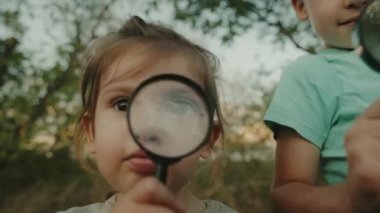 Çocuklar büyüteçle doğayı öğreniyor ve keşfediyorlar. Meraklı çocuk büyüteçten bakıyor. Erken gelişim ve beceriler.