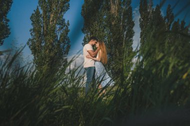 Genç romantik erkek ve kadın alacakaranlıkta birbirlerine şefkatle sarılıyorlar. Genç aşk kavramı.