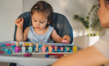 Meçhul bir anne, evde meraklı küçük bir bebekle oynuyor küçük bir çocukla komik aktiviteler yapıyor. Çocuk bakımı kavramı.