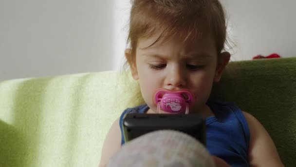 彼女が遊んでいるゲームに焦点を当てている彼女の口に太鼓を持つ赤ん坊の少女 — ストック動画