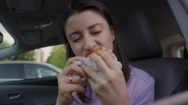 İşe gitmeden önce kahvaltıda hamburger yiyen aç beyaz kadın. Sabah yolculuğunda.