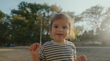 Parkta oynayan sevimli bir kız bebek, sürekli kameraya bakıyor ve onu kovalıyor, yakalamak istiyor. Komik zaman..