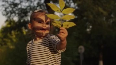 Sonbahar parkında düşen yaprakları toplayıp oynayan mutlu küçük bir kız bebek. Sonbahar sezonu
