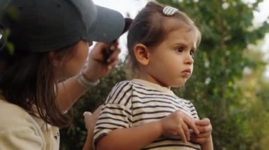 Küçük kızının yanında oturan mutlu bir annenin portresi. Evdeki yaz parkında eğleniyor ve eğleniyor. Aile birlikte hareket ediyor.