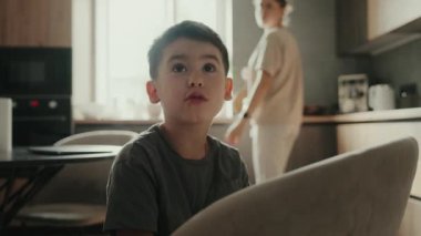 Küçük çocuk mutfakta oturuyor ve ailesiyle konuşuyor. Dinlen ve rahatla konsepti.