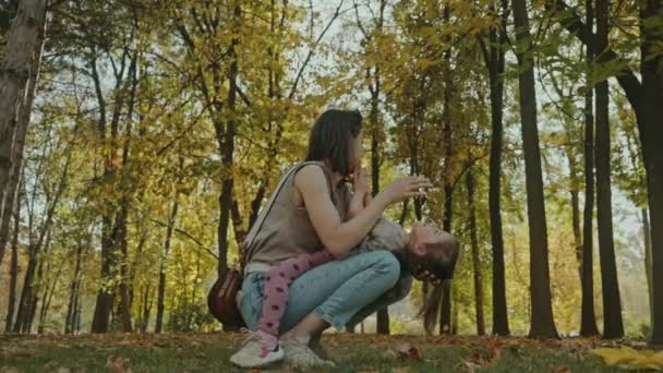 秋の公園で娘と一緒に遊び心のある瞬間を楽しんでいるお母さん 家族の楽しい貴重な瞬間 — ストック動画