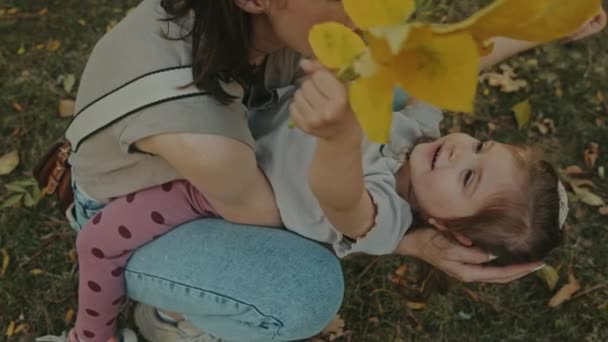 Mãe Caucasiana Segurando Sua Filha Suas Pernas Brincando Com Folhas — Vídeo de Stock