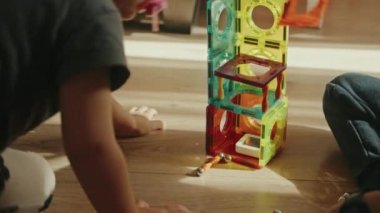 Çok renkli manyetik yapıcılarla oynayan iki çocuk bir kule inşa ediyorlar. Eğitici oyuncaklar. Oyun odası