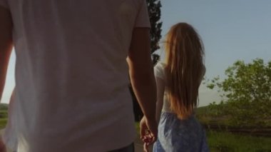 Kızıl saçlı bir kadın erkek arkadaşını arka planda elinden tutup yönlendiriyor. Mutlu insanlar. Tatil seyahati. Güzel doğa. Doğa görünümü.