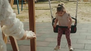 Beyaz bir anne salıncakta sallanan küçük bir kız çocuğu, dışarıda oyun alanında eğleniyor. Annemle hafta sonu..