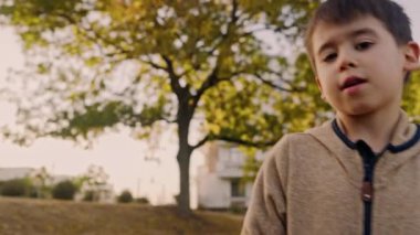 Küçük çocuk sonbahar manzarasında dışarıda yürüyor ve oynuyor. Beyaz çocuk..