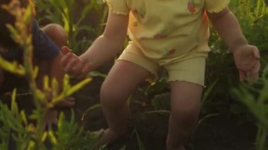 Küçük bir kızın işaret parmağında sürünen uğur böceği merakla onu inceleyip ağabeyine gösteriyor, yaz yeşilinde birlikte oynuyorlar.