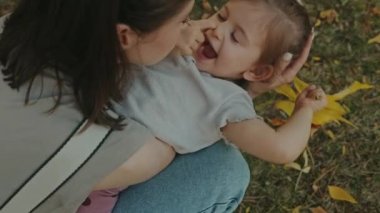 Annesinin bacaklarının üzerinde dinlenirken parkta vakit geçiren küçük bir kızın manzarası. Mutlu aile: anne ve çocuk.