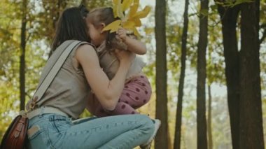 Anne lembracing küçük kız kollarında bir buket sonbahar yaprağı tutan, doğayı birlikte keşfeden. Doğa, aile, hobi konsepti.
