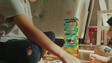 Evde oynayan iki çocuk çok renkli bir manyetik bulmacayla eğitici bir oyun oynuyorlar. Bebek çocuk odasında oynuyor. Çocukluk kavramı