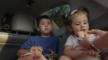 İki sevimli çocuk, ergen oğlan ve komik küçük kız, erkek ve kız kardeş, bir arabanın bagajında oturmuş aile hafta sonunun tadını çıkarıyorlar..